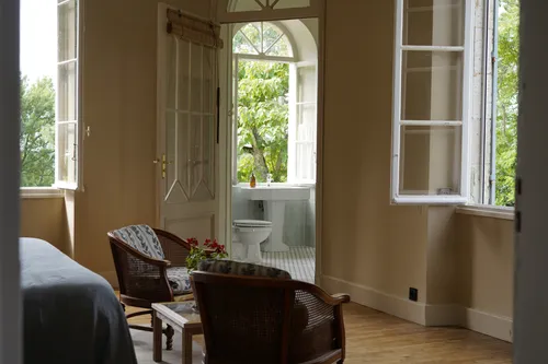 Bedroom with armchairs and views into the ensuite bathroom