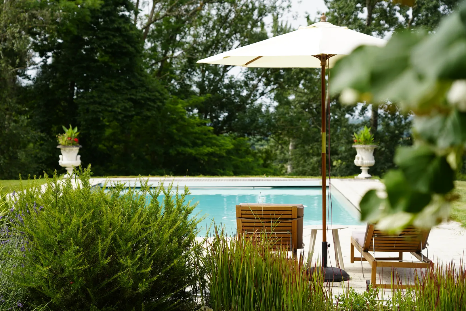 The pool at Chateau de Pomiro with deckchairs and sun umbrellar