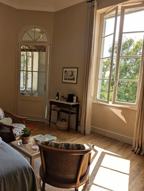 Corner of the bedroom with armchairs and sunlight from the open windows