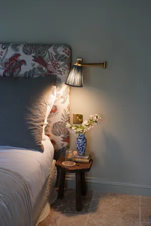 The bed in the cottage at chateau de Pomiro with cosy bedside lamp and table